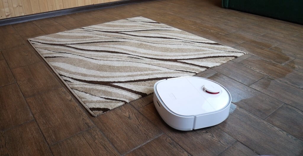 The robot vacuum cleaner goes around the carpet